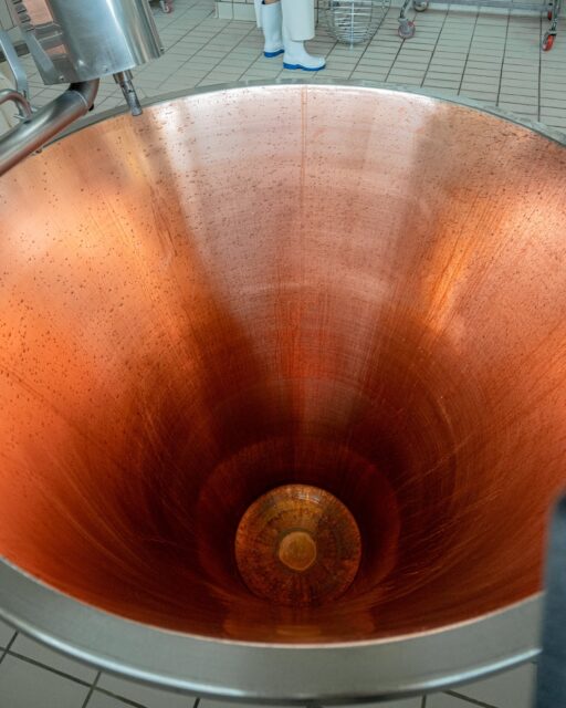 This inconspicuous cauldron from the first photo (Italian: caldaia) holds 1000L of milk, necessary to produce two, approximately 50 kilogram cylinders of cheese. The milk used to produce Parmigiano Reggiano comes from the evening milking and is skimmed, the second portion of milk is fresh, from morning milking, which is combined with whey starter - a natural carrier of lactic acid bacteria cultures (whey starter is the most natural way to induce lactic acid fermentation) - and brought to a temperature of 36°C. 

At this exact moment, the cheesemaker (Italian: casaro) adds calf rennet to the milk, which is a natural coagulant. The milk curdles within a few minutes, and the cheesemaker immediately crushes it into small granules using a tool called a spino. The cheesemaker can feel the drying of the mass with his hand, so the temperature in the cauldron cannot exceed 36-37°C - the mass must be dry, and the granules must separate from each other. At this point, the cooking process begins, the temperature in the cauldron is increased to 55°C, the cheese granules fall to the bottom of the cauldron, and whey appears on top. 

After about 20 minutes of cooking, the resulting mass is lifted from the bottom of the cauldron and transferred to a linen cloth, which will be hung above the cauldron to drain excess whey. Before the mass drains from the water, it is cut into two equal pieces called “twins” (Italian: gemelli) because only those two pieces of mass that will later become cheese will taste identical. 

After draining, each cheese mass is transferred to a form called fascera, a casein plate with an alphanumeric code is stuck on it, which is the cheese’s identity card - it contains information about the production date and the cheese factory that produced the cheese. A moment later, a plastic label is added to the form, surrounding the entire cheese – thanks to it, we have these characteristic inscriptions on Parmigiano Reggiano with information about the date of production and the cheese’s proper name.

#parmigianoreggiano #italianfoodheritage #italiancuisine #cucinaitaliana #cookingitaly #foodlover #foodwriter @parmigianoreggiano @caseificiomontecoppe